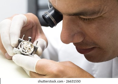 A watchmaker or repair man in action, viewing very closely a swiss watch.