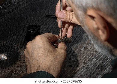 Watchmaker repairing watches looking through magnifying glass monocular. Professional senior watch fixer in repair services workshop - Powered by Shutterstock