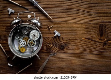 Watchmaker tools near watch mechanism of alarm clock
