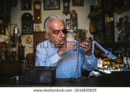 Watchmaker using a watchmaker's loupe while carefully repairing a clock mechanism in his workshop