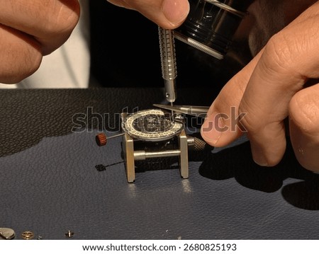 watchmaker's hands using a tool to assemble a watch