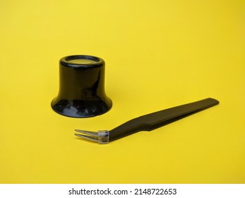 Watchmakers and jewellery loupe and tweezers on yellow background 