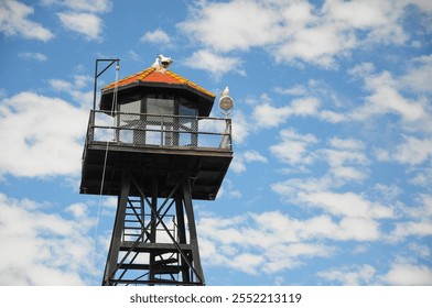 Watchtower with seagulls against vibrant blue sky with scattered clouds - Powered by Shutterstock