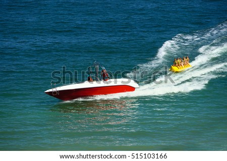 Water amusement on banana boat. summer holiday by the sea. Beautiful bright blue water and red and white boat and yellow banana boat.