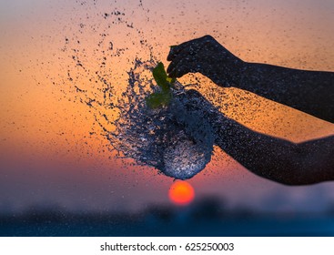 A Water Balloon Bursting Against An Orange Sky.