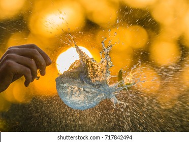 A water balloon bursting against a sunset sky.