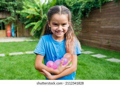 Water Balloon Games For Kids. Smiling Child Girl Holding Colorful Balls Filled With Water. Ready To Fight! Summer Fun Outdoor Activities For Children Concept