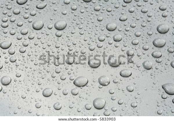 Water beads on a metallic\
grey car