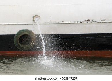 Water Being Pumped Out The Side Of A Small Boat. A Porthole Is Below And To The Left Of The Pump Hole.