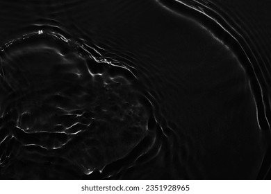 Water black surface abstract background. Waves and ripples texture of cosmetic aqua moisturizer with bubbles
