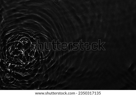 Water black surface abstract background. Waves and ripples texture of cosmetic aqua moisturizer with bubbles
