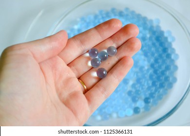 Water blue gel balls. Small gel ball in the hand. Polymer gel. Silica gel. Balls of blue hydrogel. Crystal liquid ball with reflection. Texture background. 