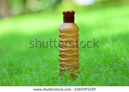 Water bottle in the grass. Transparent plastic water bottle in the grass with sunbeams. The rays of the sun shine on a water bottle