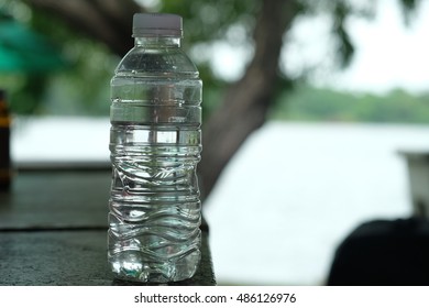 Water bottle on wooden table with bokeh background in park