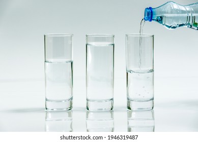 Water bottle pour water Water into three glasses - different level, on white background - three glasses of water - Shutterstock ID 1946319487