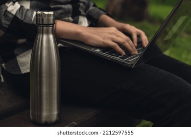 Water Bottle. Reusable Steel Thermo Water Bottle On Wooden Bench. Sustainable Lifestyle. Plastic Free Zero Waste Free Living. Go Green Woman Student Work Study With Laptop In Park 