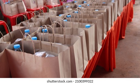 A water bottle and snacks are placed in a brown paper bag on a red table. - Powered by Shutterstock