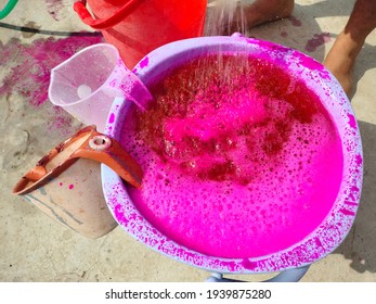 A Water Bucket Full Of Colorful Pink Essence. Celebrating The Festival Of Colors- Holi With A Plastic Container.