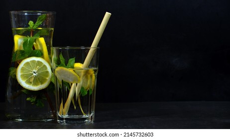 Water Carafe With Lemon And Mint And Bamboo Straw Against Dark Background