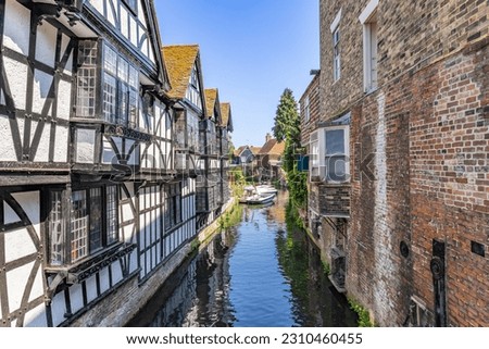 Water channel of Stour river by Canterbury, with tourist boat navigating the river. Typical buildings overlooking the Stour river in Canterbury, Kent, England, UK