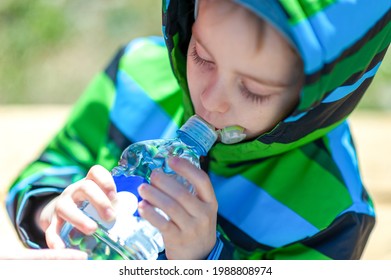 Water for children. A child boy drinks clean fresh healthy water from a bottle, quenching his thirst after active games during a walk. Give me a drink. Picture for website header. 
