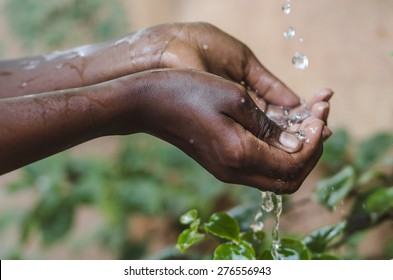 Water Climate Change Symbol: Handful Of Water Scarcity for Children Symbol. Hands Cupped under a Tap to collect water for an African girl. It is the lack of sufficient available water resources.