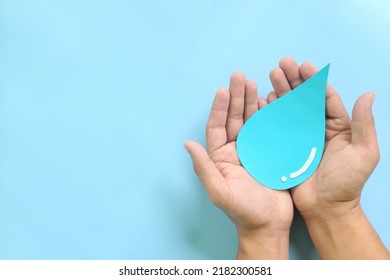 Water Conservation And Access To Safe Drinking Water Concept. Top View Of Human Hands Holding Blue Water Drop With Copy Space.