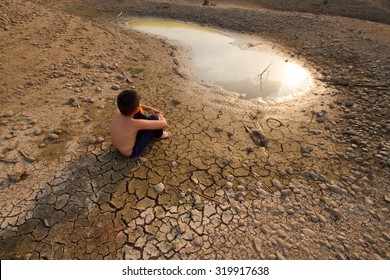 Water crisis, Child sit on cracked earth near drying water.