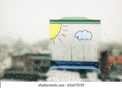 Water Cycle In A Bag. A Ziplock Plastic Bag With Water And Painted On It With A Cloud And The Sun Hanging In The Window. Clouds Form And Rain Fall In The Bag. Science Experiment For Children