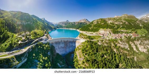 Water dam and reservoir lake aerial panoramic view in French Alps mountains generating hydroelectricity. Low CO2 footprint, decarbonize, renewable energy, sustainable development. Hydro power.