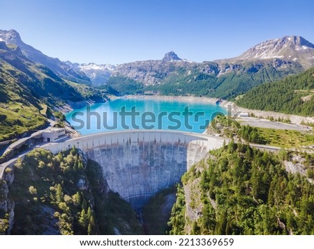 Water dam and reservoir lake aerial view in Alps mountains in summer generating hydroelectricity. Low CO2 footprint, decarbonize, renewable energy, sustainable development, hydro power.