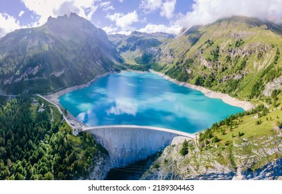 Water dam and reservoir lake in Swiss Alps mountains producing sustainable hydropower, hydroelectricity generation, renewable energy to limit global warming, aerial view, decarbonize, summer