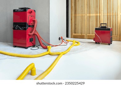 Water damage restoration service for a leaking home environment with industrial air movers, dehumidifiers and pipes to remove water and moist from the wet floor. Repair the house. Household insurance