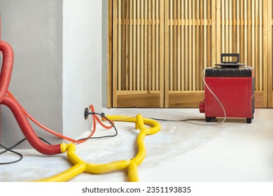 Water damage restoration service in a leaking home with industrial air movers, dehumidifiers and pipes to remove the water and moist from the wet floor and repair the house. Household insurance