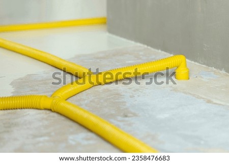 Water damage restoration service in a leaking home with industrial yellow pipes connected to air movers, dehumidifiers to remove the water and moist from the flooded wet floor. Household insurance