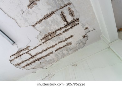 Water damaged ceiling roof in an old house. Water damage building interior. Ceiling house broken. Ceiling concrete crack and exposed the rusty steel bar frame.