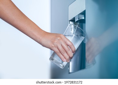 Water dispenser from dispenser of home fridge, Woman is filling a glass with water from the refrigerator. - Shutterstock ID 1972831172