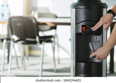 Water Dispenser In The Office, With Hand Filling A Glass Of Water 