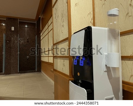 Water dispenser in the office, with hand filling a glass of water