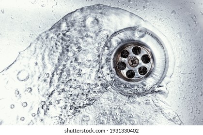 water drain down on stainless steel kitchen sink hole. top view sewer in washbasin. household plumbing. cleaning and hygiene concept. - Shutterstock ID 1931330402
