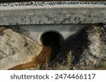 Water drain under the bridge for trains under train rails with orange contaminated water