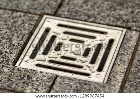 Water drain vent in kitchen, bathroom or basement ceramic tiled old vintage floor. Geometric abstract beige background.