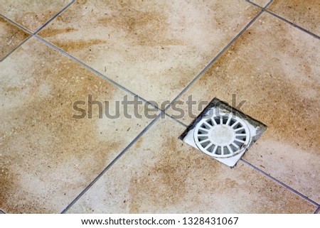 Water drain vent in kitchen, bathroom or basement ceramic tiled old vintage floor. Geometric abstract beige background.