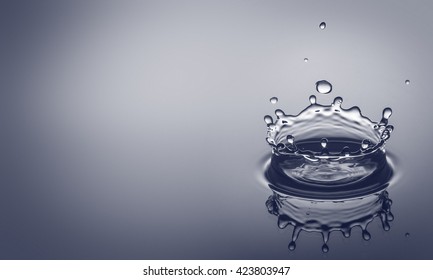 Water drip splashing a clear blue background with reflexion and room for your text.