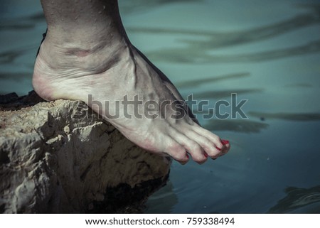 Water dripping from caucasian woman bare feet on a rock edge at the river.
