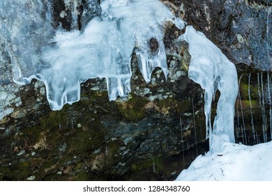 Water Dripping Down The Rock Surface On The Cliff Wall Covered In Ice