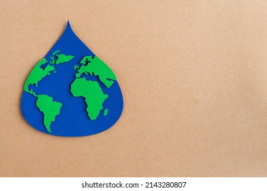 Water Drop Cut Out On Blue Paper With World Map On Brown Card Stock Background. Copy Space.