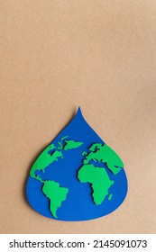 Water Drop Cut Out On Blue Paper With World Map On Brown Card Stock Background. Copy Space. Vertical Photo.