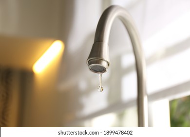 Water drop falling down from tap on blurred background, closeup