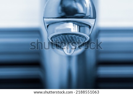 Water drop falling down from tap on blurred background, closeup